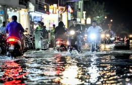 Motorcycles drive as WAMCO workers make their waste collection efforts during the heavy flooding of Male' on November 5. PHOTO: NISHAN ALI/MIHAARU