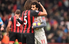 Liverpool's Egyptian midfielder Mohamed Salah (R) holding the match-ball for scoring a hat-trick is embraced by Bournemouth's Dutch defender Nathan Ake on the pitch after the English Premier League football match between Bournemouth and Liverpool at the Vitality Stadium in Bournemouth, southern England on December 8, 2018. - Liverpool won the game 4-0. (Photo by Glyn KIRK / AFP)