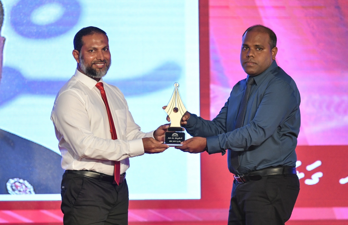 މާލެ: ޑިސެމްބަރު 11، 2018: ރާއްޖޭގެ ނޫސްވެރިކަމަށް 75 އަހަރު ފުރުމުގެ އަލިމަސްޔޫބީލް ފާހަގަ ކުރުމަށާއި ނޫސްވެރިކަމުގެ މިދިޔަ އަހަރުގެ އިނާމުތައް ދިނުމަށް މޯލްޑިވްސް މީޑިއާ ކައުންސިލާއި ހޯމް މިނިސްޓްރީ ގުޅިގެން ބޭއްވި ޖަލްސާގައި ނޫސްވެރިކަމުގެ ރަން ގަލަން ހާސިލްކުރެއްވި "މިހާރު"ގެ އެޑިޓަރު އަހުމަދު ހަމްދޫންއަށް ހޯމް މިނިސްޓަރު ޝޭހް އިމްރާން އެވޯޑު ދެއްވަނީ.---ފޮޓޯ: އަހުމަދު ނިޝާތު/މިހާރު