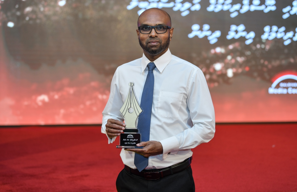 މާލެ: ޑިސެމްބަރު 11، 2018: ރާއްޖޭގެ ނޫސްވެރިކަމަށް 75 އަހަރު ފުރުމުގެ އަލިމަސްޔޫބީލް ފާހަގަ ކުރުމަށާއި ނޫސްވެރިކަމުގެ މިދިޔަ އަހަރުގެ އިނާމުތައް ދިނުމަށް މޯލްޑިވްސް މީޑިއާ ކައުންސިލާއި ހޯމް މިނިސްޓްރީ ގުޅިގެން ބޭއްވި ޖަލްސާގައި ނޫސްވެރިކަމުގެ ރަން ގަލަން ހާސިލްކުރެއްވި ބޭފުޅުންގެ ތެރެއިން މިހާރު"ގެ ސީނިއާ އެސިސްޓެންޓް އެޑިޓަރު ހަސަން އާމިރު ފޮޓޯއަކަށް ހުއްޓިލައިގެން.---ފޮޓޯ: އަހުމަދު ނިޝާތު/މިހާރު