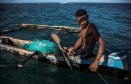 (FILES) In this file photo taken on November 4, 2018 a Malagasy fisherman takes a break as he sits in his boat while at work in the waters in front of Anakao, a traditional fishing community in southwest Madagascar. - Already threatened by the effects of the global warming, Malagasy fishermen see their traditional way of life threatened by the presence in their waters of Chinese fishing boats following the signature of a fishing agreement between Chinese investors and Madagascar parastatal entities. (Photo by MARCO LONGARI / AFP)