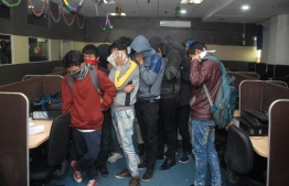 A group of the accused men allegedly involved in a scam that Indian authorities said was meant to defraud US citizens cover their faces as they stand in a call centre in Noida, some 25km east of New Delhi, on December 21, 2018. - Indian police arrested on December 21 126 people working for a allegedly fake call centre making up to $50,000 a day by duping US citizens, officials said. (Photo by - / AFP)