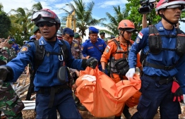 Members of an Indonesian search and rescue team carry a body bag taken from the Villa Stephanie accommodation in Carita in Banten province on December 24, 2018, two days after a tsunami - caused by activity at a volcano known as the "child" of Krakatoa - hit the west coast of Indonesia's Java island. (Photo by ADEK BERRY / AFP)