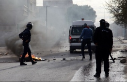 Tunisian policemen stand in a street during a demonstration on December 25, 2018 in the central Tunisian city of Kasserine. - A Tunisian journalist has died after setting himself on fire, officials said, in a protest over harsh living conditions that prompted overnight clashes with police in the country's west. Police fired tear gas at dozens of people who took to the streets Monday night in the city of Kasserine, 270 kilometres (165 miles) from the capital, setting tyres ablaze and blocking the main street. (Photo by Hatem SALHI / AFP)