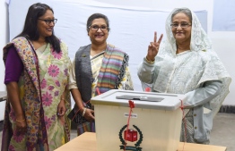 Bangladeshi Prime Minister Sheikh Hasina (R) flashes the victory symbol after casting her vote, as her daughter Saima Wazed Hossain (1st L) and her sister Sheikh Rehana (2nd L) look on at a polling station in Dhaka on December 30, 2018. - Bangladesh headed to the polls on December 30 following a weeks-long campaign that was dominated by deadly violence and allegations of a crackdown on thousands of opposition activists. (Photo by AFP)