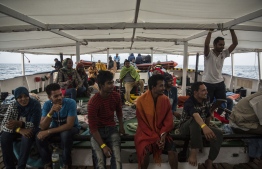 (FILES) In this file photo taken on July 2, 2018 migrants wait on the deck of the NGO Proactiva Open Arms boat after being rescued as they tried to cross the Mediterranean from Libya. - The number of migrants who died attempting to cross the Mediterranean fell by more than a quarter in 2018 over the previous year, with 2,262 people reported dead or missing, the UN refugee agency said on January 3, 2019. The number of migrants who arrived in Europe after surviving the sea crossing also dropped by roughly the same amount last year to 113,482  after 172,301 in 2017, according to the agency's full-year figures. (Photo by Olmo Calvo / AFP)