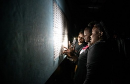 Late voters check a list after arriving at a polling station at Kiwele college in Lubumbashi on December 30, 2018, shortly before the close of polls in the country's presidential, provincial and national elections. - After two years of delays, the Democratic Republic of Congo voted December 30 in presidential elections that will determine the future of Africa's notoriously unstable giant. (Photo by Caroline Thirion / AFP)