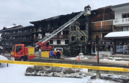 Firefighters and French gendarmes stand in front of a building destroyed by a major fire which killed two people and injured 22 more, on January 20, 2019 at the ski resort of Courchevel in the French Alps. - The pre-dawn blaze forced the evacuation of some 60 resort workers, including foreigners, from a three-storey accommodation building. Firemen found the two unidentified bodies in a burnt-out area of the building in the upmarket Courchevel 1850 ski station. (Photo by Fanny HARDY / AFP)