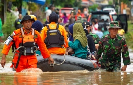Indonesian rescuers evacuate residents from their homes in Makassar on January 24, 2019 as heavy rain and strong winds pounded the southern part of Sulawesi island, swelling rivers that burst their banks and inundating dozens of communities in nine southern districts. - The death toll from flash floods and landslides in Indonesia jumped to 26, a disaster agency official said on January 24, as rescuers race to find still-missing victims. (Photo by YUSUF WAHIL / AFP)