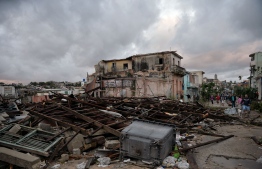 Residents walk amid the debris from their destroyed homes, after the passage of a tornado in Havana, on January 28, 2019. - A rare and powerful tornado that struck Havana killed three people and left 172 injured, Cuban President Miguel Diaz-Canel said early Monday. (Photo by YAMIL LAGE / AFP)