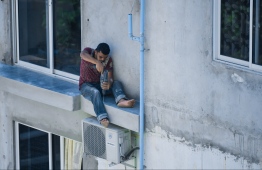 An expatriate worker operates on a small balcony of an apartment building without the use of safety equipment. PHOTO: HUSSAIN WAHEED / MIHAARU