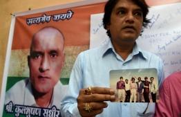 (FILES) In this file photo taken on May 18, 2017 Indian friends of Kulbhushan Jadhav hold a photograph of them with Jadhav in the neighborhood where he grew up in Mumbai on May 18, 2017. - India will ask the UN's top court on February 18, 2019, to order Pakistan to take an alleged Indian spy off death row, in a case that could stoke fresh tensions after a deadly attack in Kashmir. Kulbhushan Sudhir Jadhav was arrested in the restive southwestern Pakistani province of Baluchistan in March 2016 on charges of espionage and sentenced to death by a military court. (Photo by PUNIT PARANJPE / AFP)