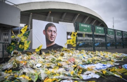 (FILES) In this file photo taken on February 08, 2019 yellow flowers are displayed in front of the portrait of Argentinian forward Emiliano Sala at the Beaujoire stadium in Nantes, France. - Argentine footballer Emiliano Sala's body is to be returned to Argentina on Friday for his wake at the Club Atletico y Social San Martin in his hometown Progreso, Santa Fe province. Sala's body was recovered from plane wreckage in the English Channel last week. He was flying to his new team, English Premier League side Cardiff City, from his old French club Nantes when his plane went missing over the Channel on January 21. (Photo by LOIC VENANCE / AFP)