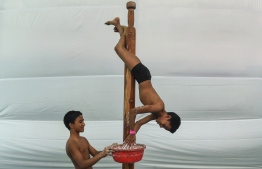In this photo taken on February 16, 2019, a young Indian gymnast trains on a pole ahead of the Mallakhamb World Championships in Mumbai. - Some 100 competitors from 15 different countries take part in the Mallakhamb World Championships in India's financial capital of Mumbai on February 16 and 17. Mallakhamb is a gymnastics-like discipline that originated in western India in the 12th century and is often described as "yoga on a pole". (Photo by PUNIT PARANJPE / AFP) / 