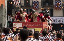 Members of orange battle teams throw oranges at each other during the traditional "battle of the oranges" held during the carnival in Ivrea, near Turin, on March 3, 2019. - During the event, which marks the people's rebellion against tyrannical lords who ruled the town in the Middle Ages, revellers parading on floats represent guards of the tyrant, while those on foot the townsfolk. (Photo by MARCO BERTORELLO / AFP)