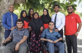 Bank of Maldives staff posing for a picture with recipients of the Motorised Wheelchair Donation programme. PHOTO: BANK OF MALDIVES