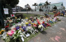 Residents pay their respects by placing flowers for the victims of the mosques attacks in Christchurch at the Masjid Umar mosque in Auckland on March 17, 2019. - The death toll from horrifying shootings at two mosques in New Zealand rose to 50, police said Sunday, as Christchurch residents flocked to memorial sites and churches across the city to lay flowers and mourn the victims. (Photo by MICHAEL BRADLEY / AFP)