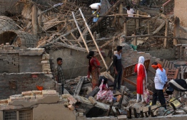 Nepali villagers search for belongings in the debris of damaged homes at Bhaluhi Bharbaliya village in Nepal's southern Bara district near Birgunj on April 1, 2019, the morning after a rare spring storm. - A freak storm tore down houses and overturned cars and trucks as it swept across southern Nepal killing at least 27 people and leaving more than 600 injured, officials said on April 1 as a major rescue operation gathered pace. (Photo by PRAKASH MATHEMA / AFP)