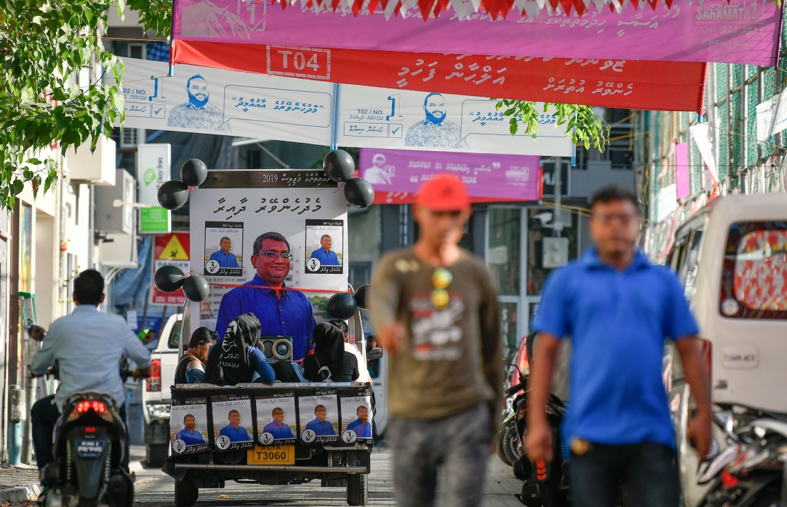 ކެމްޕޭން ހަރަކާތަށް ޖަރީކޮށްފައި އޮތް ޕިކަޕެއް، ގިނައަދަދެއްގެ ބެނާ ދަމާފައިއޮތް މަގެއްގެ މަތިން ދުއްވާފައި ދަނީ.---ފޮޓޯ: ނިޝާން އަލީ/މިހާރު