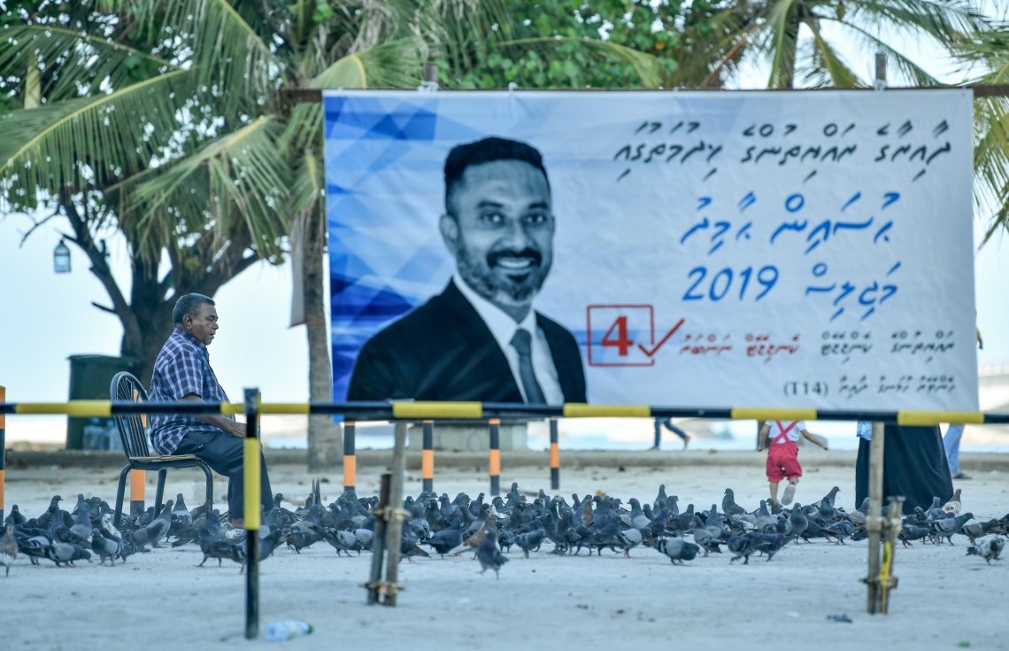 އާޓިފިޝަލް ބީޗު ސަރަހައްދުގައި ކޮތަރަށް ކާންދޭން މީހަކު މަޑުކޮށް؛ައިގެން އިން އިރު ކައިރީގައި ކެމްޕޭން ބިލްބޯޑެއް ބަހަައްޓާފައި.---ފޮޓޯ: ނިޝާން އަލީ/މިހާރު