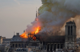 Smoke billows as flames burn through the roof of the Notre-Dame de Paris Cathedral on April 15, 2019, in the French capital Paris. - A huge fire swept through the roof of the famed Notre-Dame Cathedral in central Paris on April 15, 2019, sending flames and huge clouds of grey smoke billowing into the sky. The flames and smoke plumed from the spire and roof of the gothic cathedral, visited by millions of people a year. A spokesman for the cathedral told AFP that the wooden structure supporting the roof was being gutted by the blaze. (Photo by Fabien Barrau / AFP)