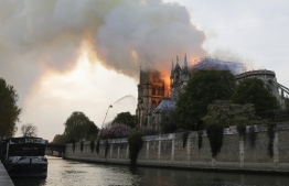Flames and smoke are seen billowing from the roof at Notre-Dame Cathedral in Paris on April 15, 2019. - A fire broke out at the landmark Notre-Dame Cathedral in central Paris, potentially involving renovation works being carried out at the site, the fire service said. (Photo by Thomas SAMSON / AFP)