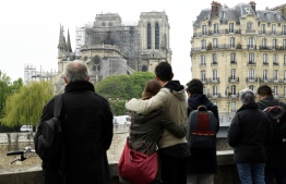 People hug while looking at Notre-Dame-de-Paris on April 16, 2019 in the aftermath of a fire that devastated the cathedral. - Paris was struck in its very heart as flames devoured the roof of Notre-Dame, the medieval cathedral made famous by Victor Hugo, its two massive towers flanked with gargoyles instantly recognisable even by people who have never visited the city. (Photo by Bertrand GUAY / AFP)