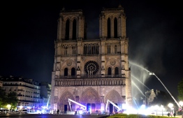 Fire fighter douse the Notre-Dame de Paris Cathedral after a fire broke out on April 15, 2019, in the French capital Paris. - A huge fire swept through the roof of the famed Notre-Dame Cathedral in central Paris on April 15, 2019, sending flames and huge clouds of grey smoke billowing into the sky. The flames and smoke plumed from the spire and roof of the gothic cathedral, visited by millions of people a year. A spokesman for the cathedral told AFP that the wooden structure supporting the roof was being gutted by the blaze. (Photo by STEPHANE DE SAKUTIN / AFP)