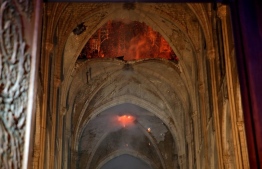 Flames and smoke are seen as the interior of the Notre-Dame Cathedral continues to burn on April 15, 2019, in the French capital Paris. - A huge fire swept through the roof of the famed Notre-Dame Cathedral in central Paris on April 15, 2019, sending flames and huge clouds of grey smoke billowing into the sky. The flames and smoke plumed from the spire and roof of the gothic cathedral, visited by millions of people a year. A spokesman for the cathedral told AFP that the wooden structure supporting the roof was being gutted by the blaze. (Photo by PHILIPPE WOJAZER / POOL / AFP)