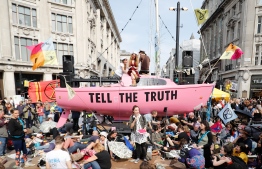 Climate change activists listen to speeches at their encampment blocking the road junction at Oxford Circus in the busy shopping district in central London on April 18, 2019 during the fourth day of an environmental protest by the Extinction Rebellion group. - London commuters faced further disruption on Thursday as climate change protests continued to bring parts of the British capital to a standstill, leading to over 300 arrests. Demonstrators began blocking off a bridge and major central road junctions on April 15 at the start of a civil disobedience campaign calling for governments to declare an ecological emergency over climate change, to reduce greenhouse gas emissions to zero by 2025, halt biodiversity loss and be led by new "citizens' assemblies on climate and ecological justice". (Photo by Tolga AKMEN / AFP)