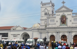 Ambulances are seen outside the church premises with gathered people and security personnel following a blast at the St. Anthony's Shrine in Kochchikade, Colombo on April 21, 2019. - Explosions have hit three churches and three hotels in and around the Sri Lankan capital of Colombo, police said on April 21. (Photo by ISHARA S.  KODIKARA / AFP)