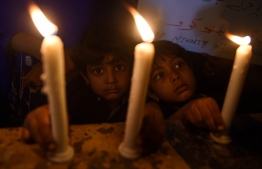 Pakistani Christian children light candles to pay tribute to Sri Lankan blasts victims in Karachi on April 21, 2019. - A series of eight devastating bomb blasts ripped through high-end hotels and churches holding Easter services in Sri Lanka on April 21, killing at least 207 people, including dozens of foreigners. (Photo by RIZWAN TABASSUM / AFP)