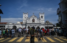 Local residents gather outside the St. Anthony's Shrine in Colombo on April 22, 2019, a day after the building was hit as part of a series of bomb blasts targeting churches and luxury hotels in Sri Lanka. - The death toll from bomb blasts that ripped through churches and luxury hotels in Sri Lanka rose dramatically April 22 to 290 -- including dozens of foreigners -- as police announced new arrests over the country's worst attacks for more than a decade. (Photo by Mohd RASFAN / AFP)