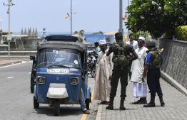 Soldiers search a three-wheeler as passengers look on at a checkpoint on a street in Colombo on April 25, 2019, following a series of bomb blasts targeting churches and luxury hotels on the Easter Sunday in Sri Lanka. - Sri Lanka's Catholic churches suspended all public services over security fears on April 25, as thousands of troops joined the hunt for suspects in deadly Easter bombings that killed nearly 360 people. (Photo by Jewel SAMAD / AFP)