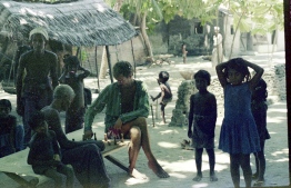 Frank playing chess with an elderly man of the island while children plays around him. PHOTO: FRANK BURNABY