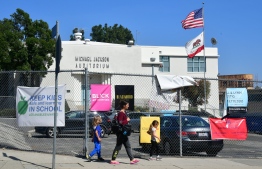 Pedestrians walk past the Michael Jackson Auditorium at Gardner Street Elementary school in Hollywood, California on April 25, 2019. - Los Angeles elementary school parents decide April 26, 2019 if their auditorium will stop bearing Michael Jackson's name after the controversial documentary accusing him of sexual abuse. The school's auditorium, located in Hollywood, was named after the king of pop in 1989. At age 11, Jackson attended Gardner Elementary for a few months before his first Jackson 5 single "I Want You Back" made them famous in 1969. (Photo by Frederic J. BROWN / AFP)