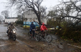 Indian residents ride along a road next to damaged trees oafter Cyclone Fani landfall in Puri in the eastern Indian state of Odisha on May 3, 2019. - Two people died on May 3 after Cyclone Fani slammed into eastern India, officials said, as the storm sent coconut trees flying, blew away food stands and cut off power and water. The monster weather system, which made landfall at the eastern holy city of Puri in the morning, is one of the strongest to come in off the Indian Ocean in years, with winds gusting at speeds of up to 200 kilometres (125 miles) per hour. (Photo by Dibyangshu SARKAR / AFP)