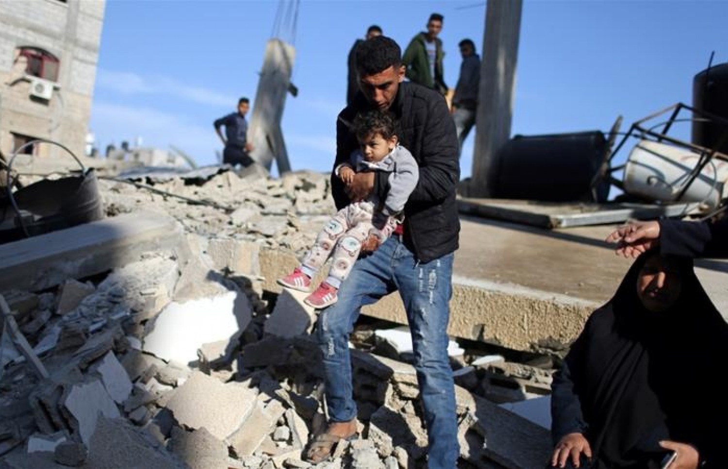 ރޮކެޓް ހަމަލާތަކުގައި ވެއްޓިފައިވާ އިމާރާތެއްގެ ބައިތަކުގެ ތެރޭން ކުޑަ ކުއްޖަކު ގޮވައިގެން މީހަކު ދަނީ. --ފޮޓޯ:ރޮއިޓާސް