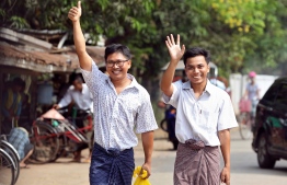 Reuters journalists Wa Lone (L) and Kyaw Soe Oo gesture as they walk to Insein prison gate after being freed in a presidential amnesty in Yangon on May 7, 2019. - Two Reuters journalists who had been jailed for their reporting on the Rohingya crisis in Myanmar walked out of prison on May 7, freed in a presidential amnesty after a global campaign for their release. (Photo by ANN WANG / POOL / AFP)