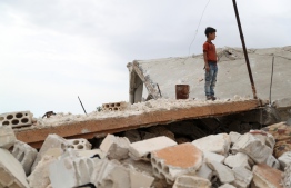 A Syrian boy stands above the rubble of a building in the village of Rabaa Jour in the the jihadist-held Syrian province of Idlib on May 6, 2019 following reported shelling and air strikes in the area. - Clashes between Syrian regime forces and jihadists killed more than 26 fighters in the country's northwest, which has seen an escalation in shelling and air strikes, a monitor said. (Photo by OMAR HAJ KADOUR / AFP)