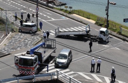Police officers remove vehicles that ploughed into a group of kindergarten children leaving at least four of them critically injured at a crossing in Otsu, Shiga prefecture on May 8, 2019. - JAPAN OUT (Photo by JIJI PRESS / JIJI PRESS / AFP) / 