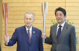 Japanese Prime Minister Shinzo Abe (R) and Tokyo 2020 Olympic and Paralympic games organising committee president Yoshiro Mori (L) pose while holding Olympic torches at Abe's official residence in Tokyo on May 9, 2019. - JAPAN OUT (Photo by JIJI PRESS / JIJI PRESS / AFP) / 