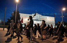 Anti-authoriterian protesters march in front of the Greek parliament in Athens on May 14, 2019 during a demonstration in support to hunger-striking far-left extremist serving 11 life terms for a string of murders, Dimitris Koufodinas, chief hit man for the November 17 group. - Koufodinas, 61, is in hospital due to the hunger strike he started May 2, after authorities in his prison  rejected again his furlough request. (Photo by LOUISA GOULIAMAKI / AFP)