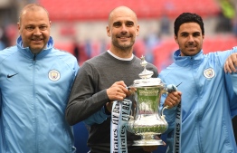 Manchester City's Spanish manager Pep Guardiola (C) holds the winner's trophy as the team celebrates victory after the English FA Cup final football match between Manchester City and Watford at Wembley Stadium in London, on May 18, 2019. - Manchester City beat Watford 6-0 at Wembley to claim the FA Cup. (Photo by Daniel LEAL-OLIVAS / AFP) / NOT FOR MARKETING OR ADVERTISING USE / RESTRICTED TO EDITORIAL USE