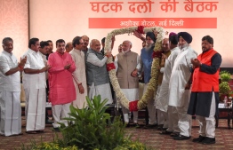 Indian Prime Minister Narendra Modi (C) gestures as he is garlanded by Bharatiya Janata Party (BJP) and other alliance leaders during the National Democratic Alliance (NDA) dinner meeting in New Delhi on May 21, 2019. (Photo by Money SHARMA / AFP)