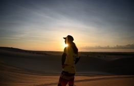 This photograph taken on April 24, 2019 shows snowboarder Nguyen Thai Binh looking at sand dunes in the southern Vietnamese town of Mui Ne. - Sun-kissed and shaggy haired, Nguyen Thai Binh swaps his flip flops for bulky boots ahead of snowboarding practice on the sand dunes of southern Vietnam -- the unlikely training ground for the country's fledgling winter athletes with mountain-sized ambitions. (Photo by Manan VATSYAYANA / AFP) / 