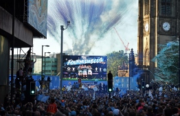 Manchester City football fans line the streets as they try to see the team show off their trophies on a stage, following an open-top bus parade through Manchester, northern England on May 20, 2019, to celebrate winning the 2019 Premier League title, the FA Cup and English League Cup. - Pep Guardiola saluted Manchester City's history makers after they clinched the domestic treble with a swaggering 6-0 rout of Watford in the FA Cup final on Saturday. Just a week after winning a second successive Premier League crown, City's record-equalling FA Cup final victory made them the first English club to win the English title, FA Cup and League Cup in the same season. (Photo by Oli SCARFF / AFP)