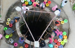 (FILES) In this file photo taken on May 29, 2019, Indian residents fetch drinking water from a well in the outskirts of Chennai. - Temperatures pushed towards 50 degrees Celsius (122 Fahrenheit) across much of India on June 1 as an unrelenting heatwave triggered warnings of water shortages and heat stroke. (Photo by ARUN SANKAR / AFP)