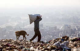 (FILES) In this file photo taken on April 14, 2018, an Indian rag picker carries a sack of sorted recyclable materials atop the Ghazipur landfill site in the east of New Delhi. - India's tallest rubbish mountain in New Delhi is on course to rise higher than the Taj Mahal in the next year, becoming a fetid symbol for what the UN considers the world's most polluted capital. (Photo by XAVIER GALIANA / AFP)