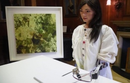 Robot artist 'Ai-Da' sketches using a pencil attached to her robotic arm, while standing next to a painting based on her computer vision data when run through algorithms developed by computer scientists in Oxford, Britain June 4, 2019. PHOTO: REUTERS/Matthew Stock